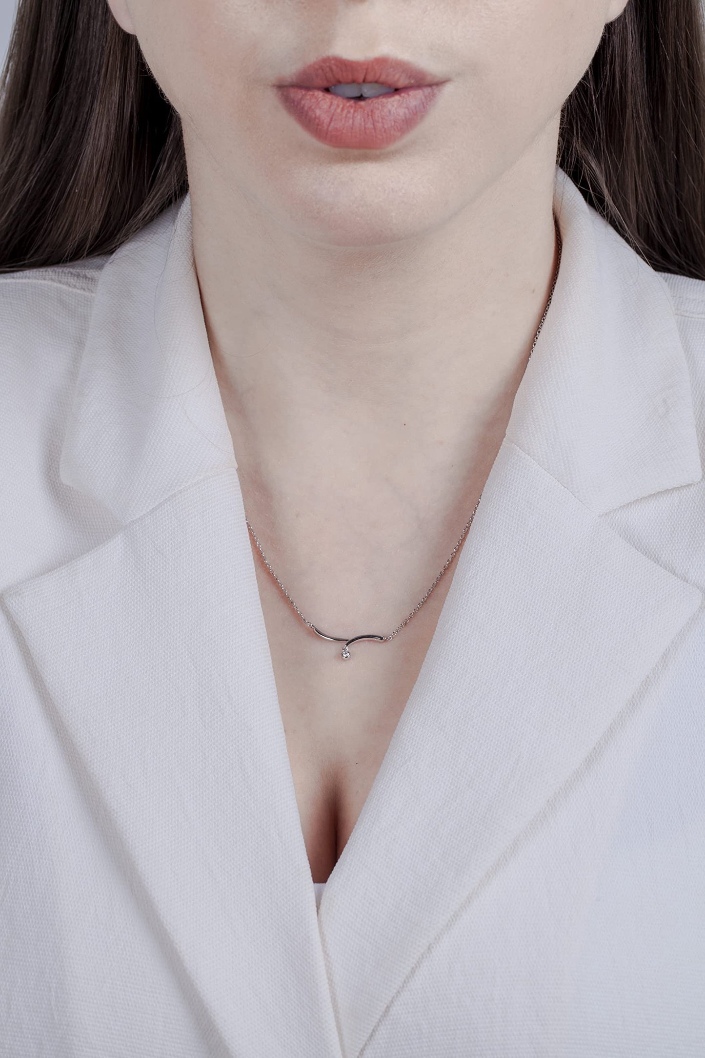 Model wearing a Sterling silver drop wave necklace pendant featuring a round brilliant cut, canadian diamond solitaire.