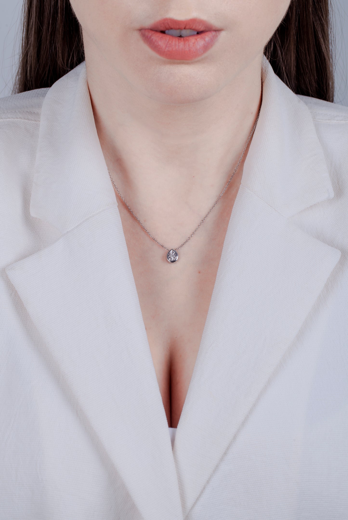 model wearing a Sterling silver pear shaped pendant featuring a round brilliant cut, canadian diamond set in a miracle illusion setting.