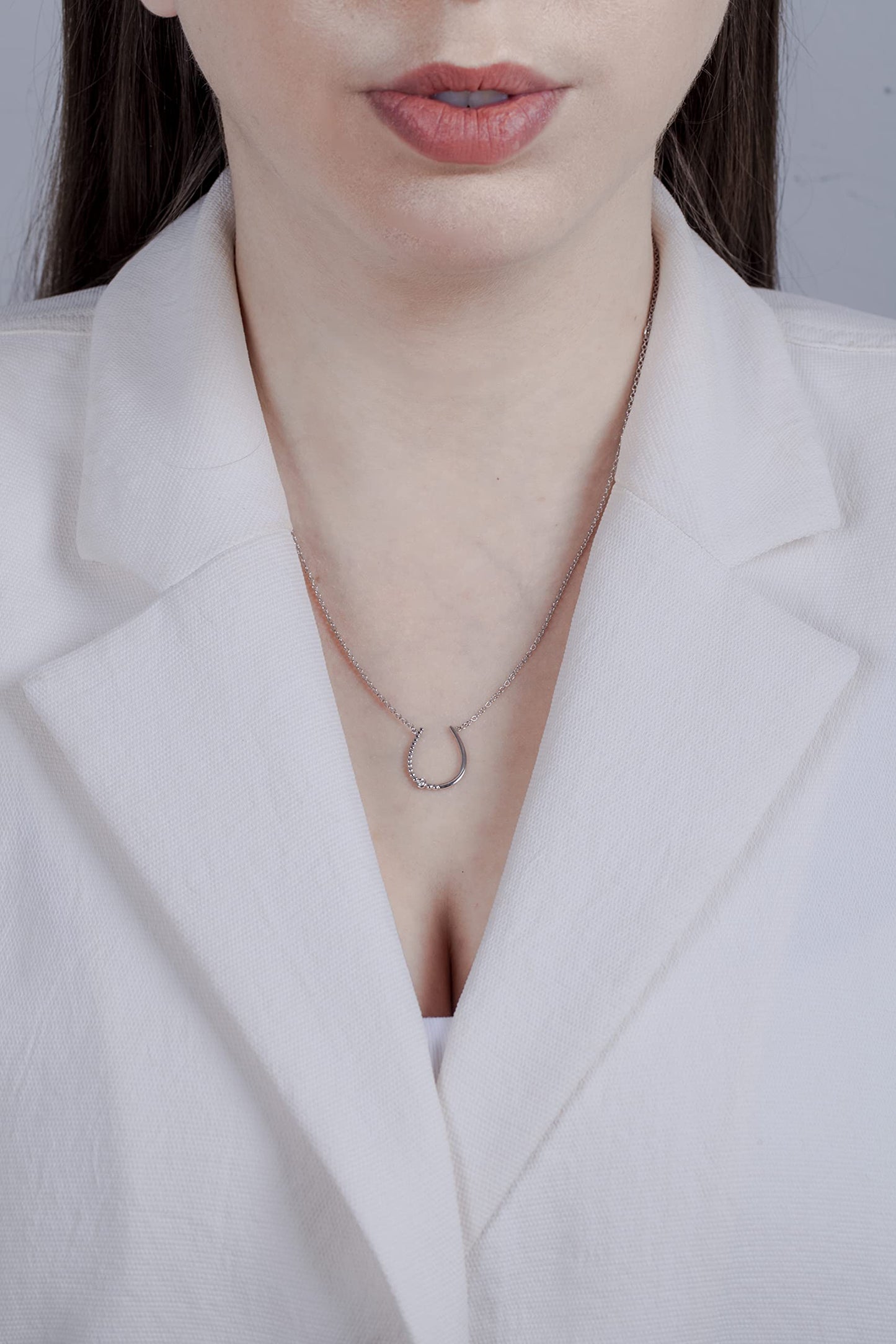 Model wearing a Sterling silver horseshoe lucky charm pendant featuring a round brilliant cut, canadian diamond.