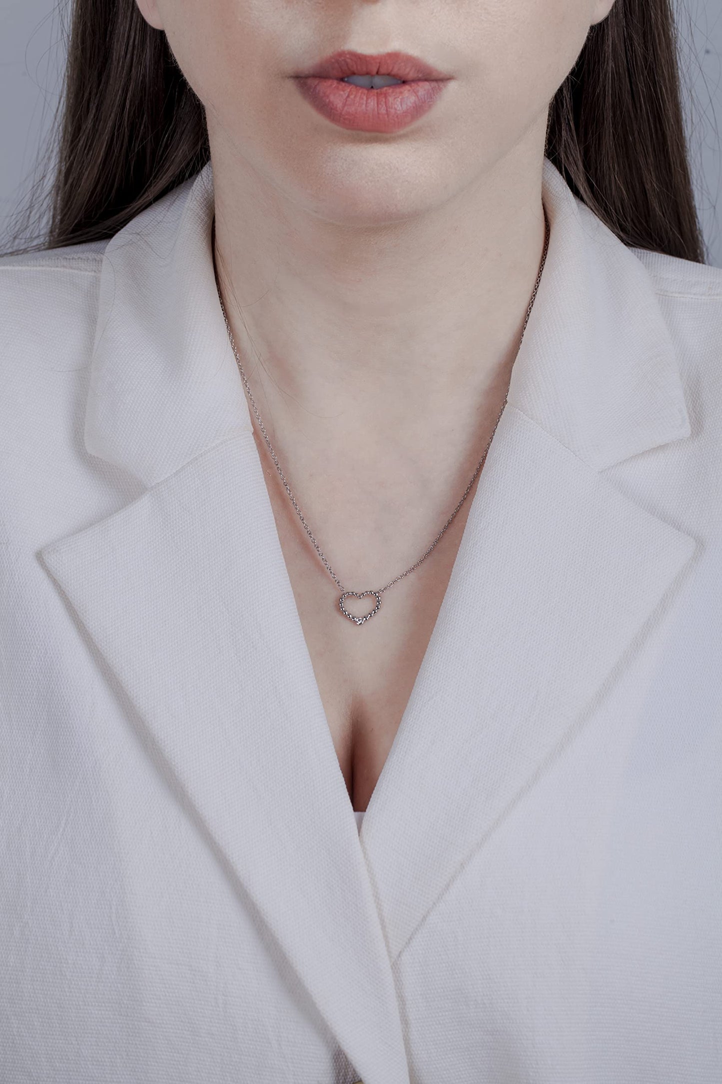 Model wearing a Sterling silver heart pendant featuring a round brilliant cut, canadian diamond.