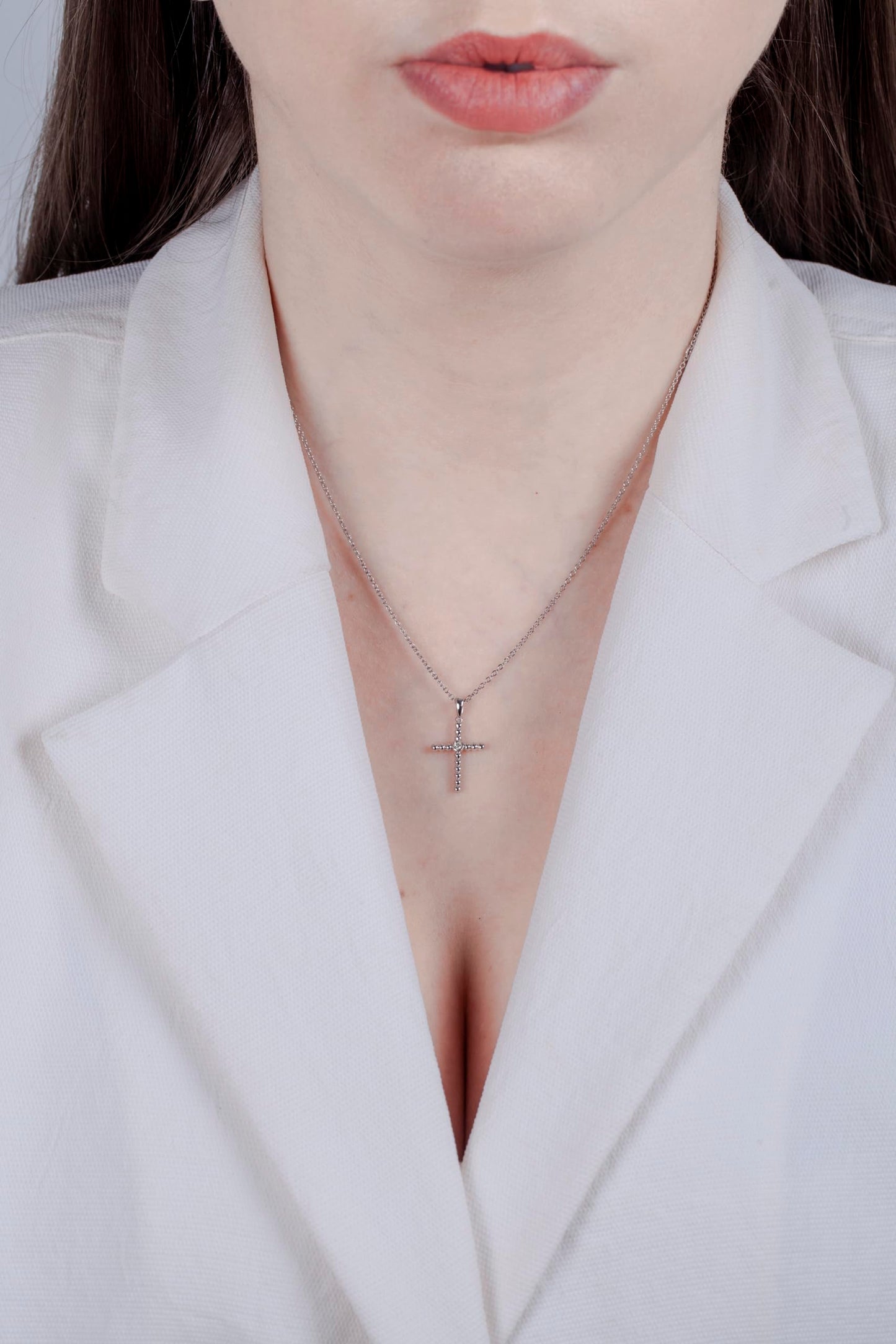 Model wearing a Sterling silver cross pendant featuring a round brilliant cut, canadian diamond in the center.