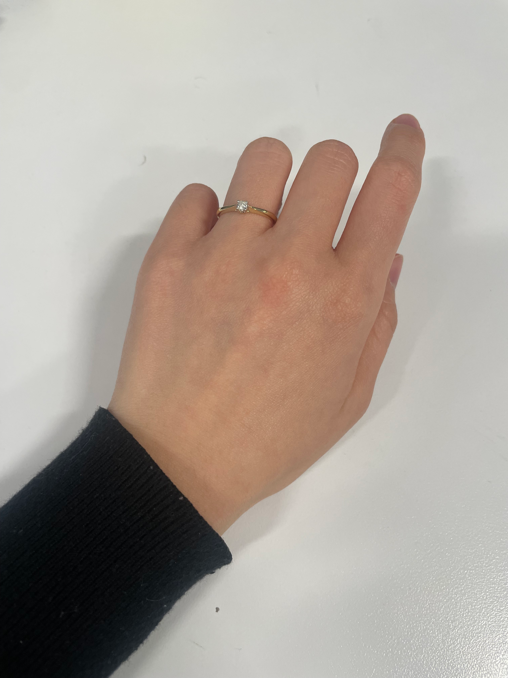 Model wearing a solitaire engagement ring in 10k yellow gold on ring finger, featuring a 0.10 carat Canadian diamond.