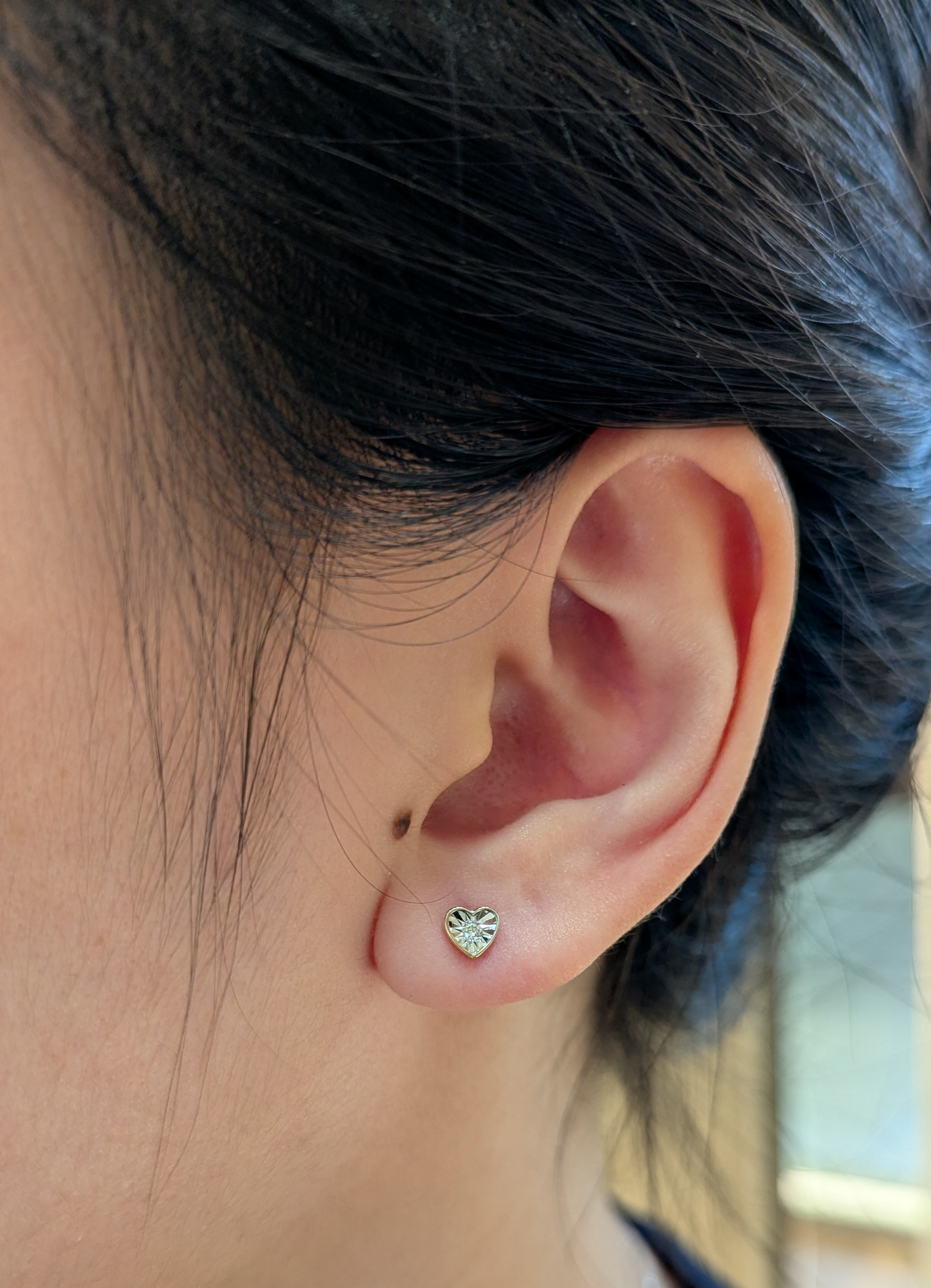 10K yellow gold 0.04 cttw Canadian diamond dainty heart shaped stud earring on ear model.