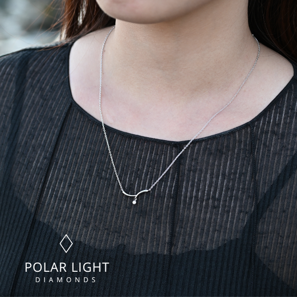 Model wearing a sterling silver wave necklace with a single Canadian diamond accent, featuring the Polar Light Diamonds brand logo.
