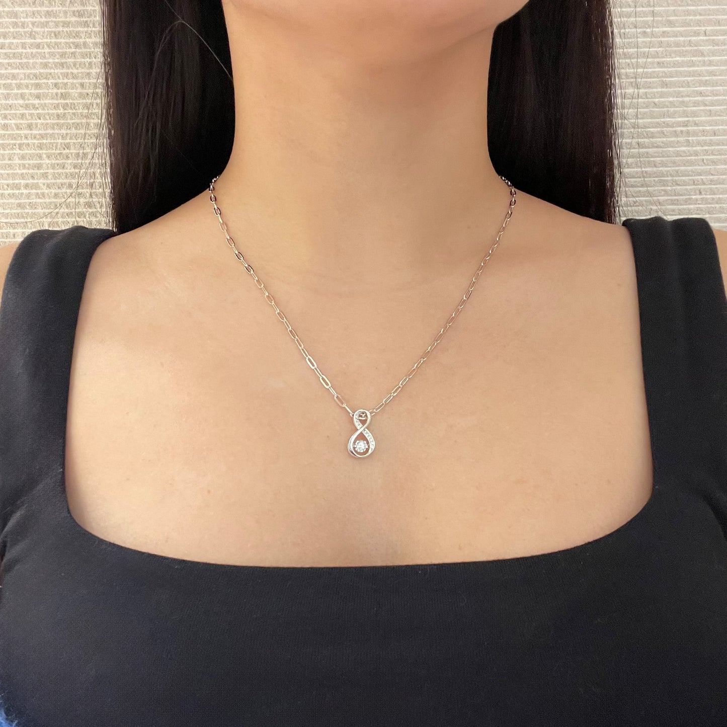 High-polish 925 sterling silver vertical infinity pendant featuring natural Canadian diamonds. A central 'dancing' diamond is suspended in a miracle setting to catch the light with every movement, hung from a trendy sterling silver paperclip link chain for a modern, minimalistic look.