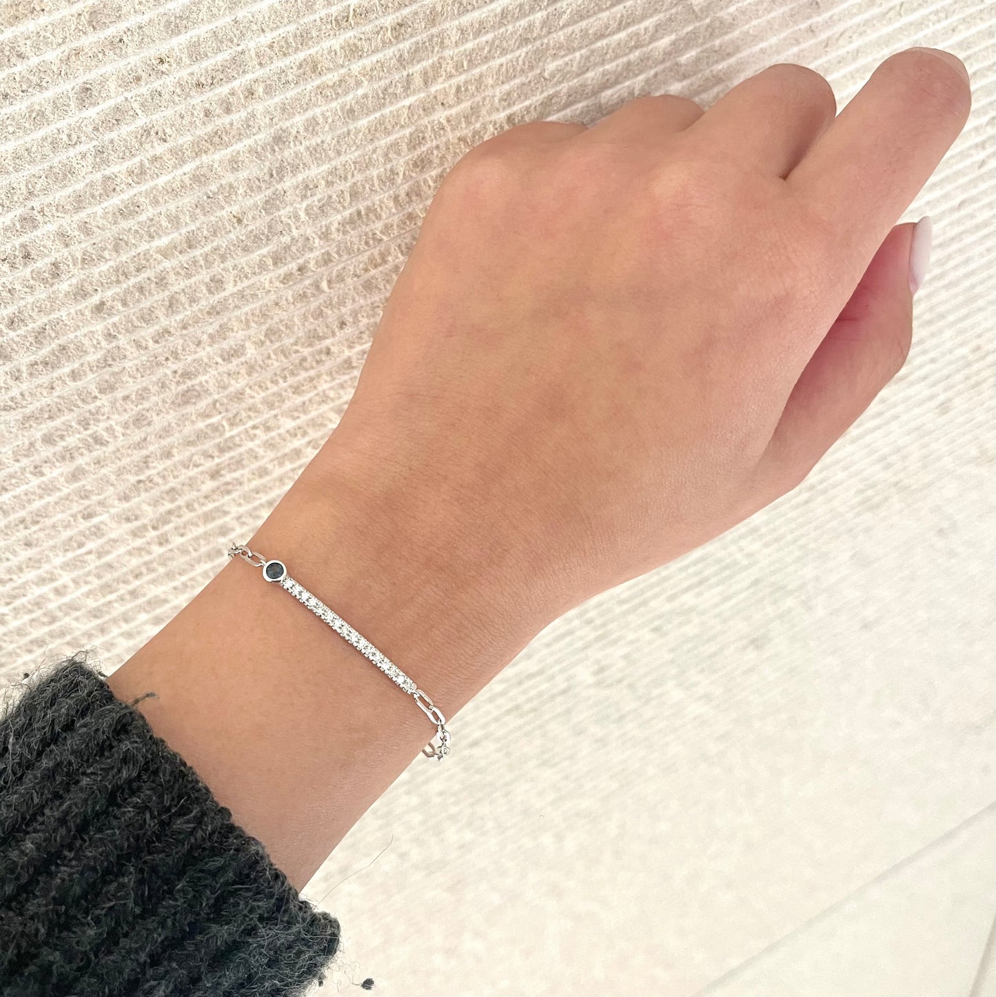 Sterling silver paperclip bracelet with sapphire and Canadian diamond line design on a wrist for reference