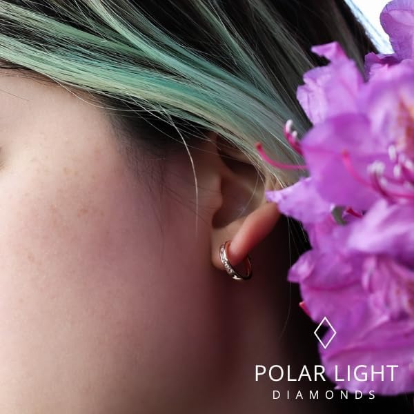 Close-up of a model wearing a 10K rose gold hoop earring set with natural pink sapphires and Canadian diamonds. The earring is pictured next to a vibrant purple flower to highlight the warm pink tones, featuring the 'Polar Light Diamonds' logo in the corner.