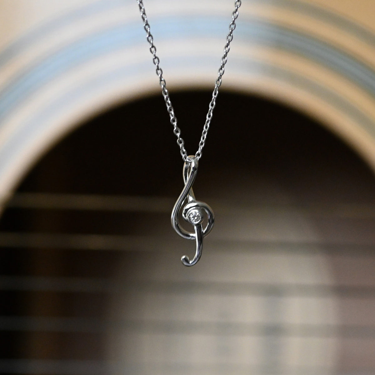 Music note Canadian diamond sterling silver pendant with a blurred guitar in the background