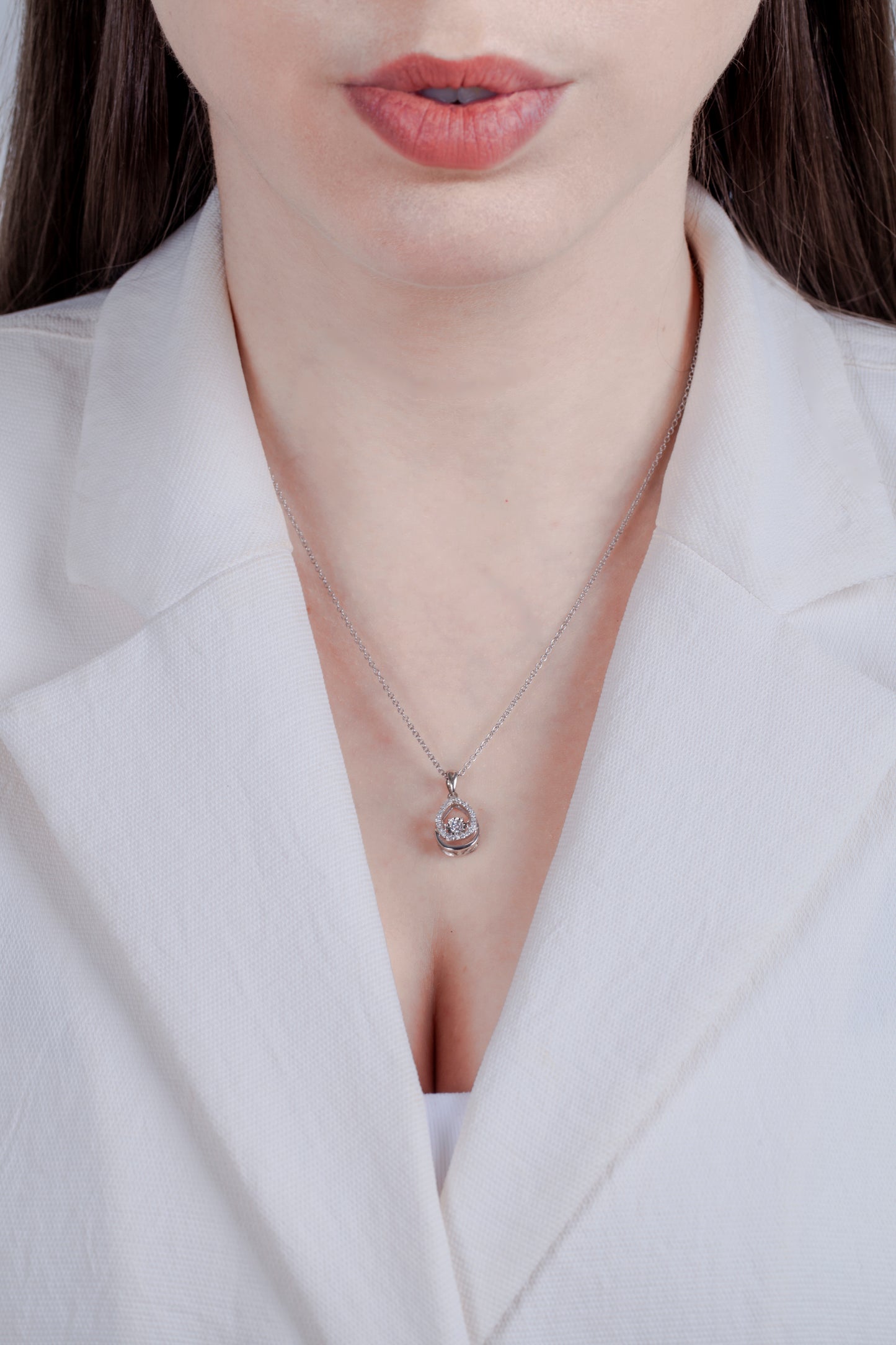 Teardrop diamond necklace with dancing center worn by model in a white blazer.
