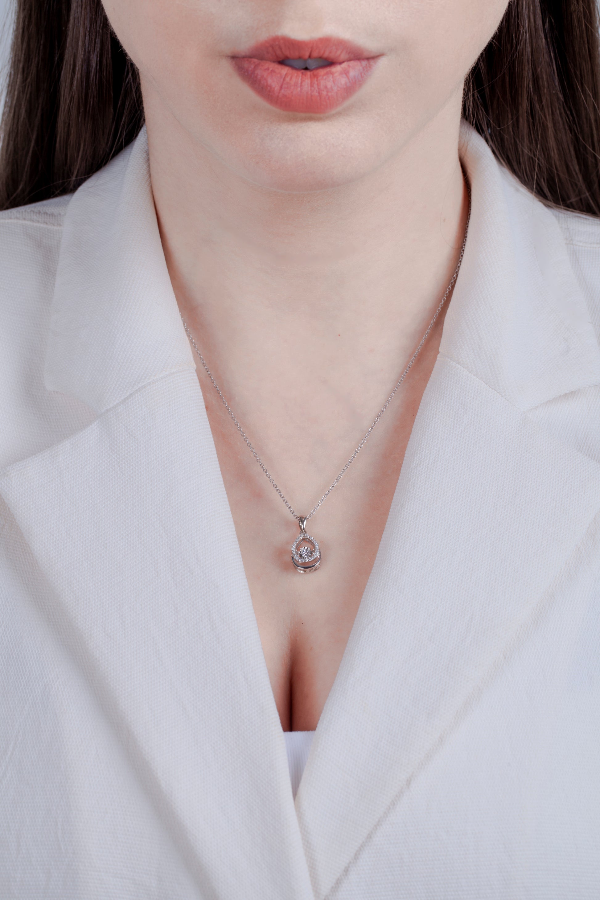 Teardrop diamond necklace with dancing center worn by model in a white blazer.