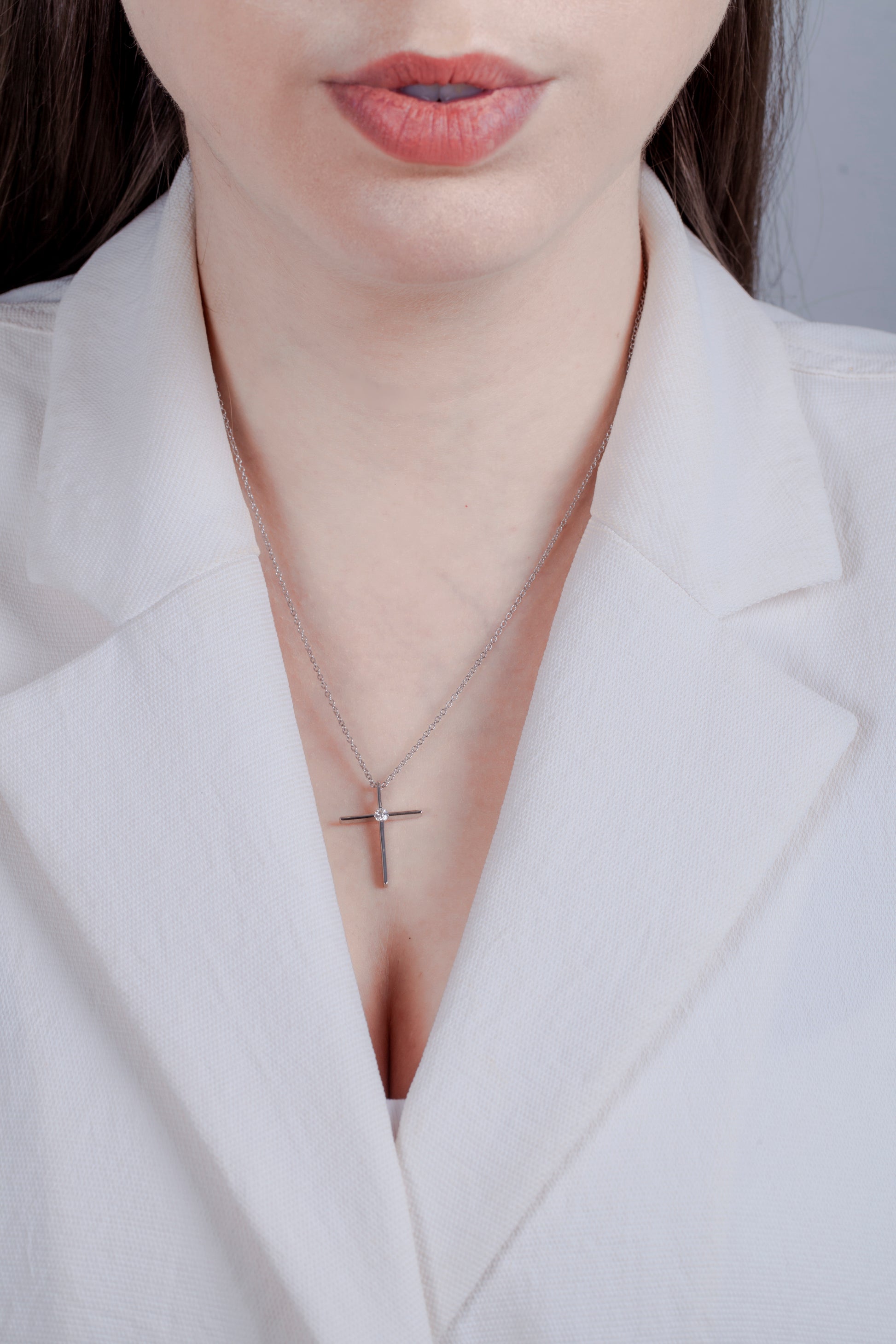 925 sterling silver Canadian diamond cross pendant on a model. Minimalist jewelry styling featuring a dainty silver cross and rolo chain with a professional white outfit.