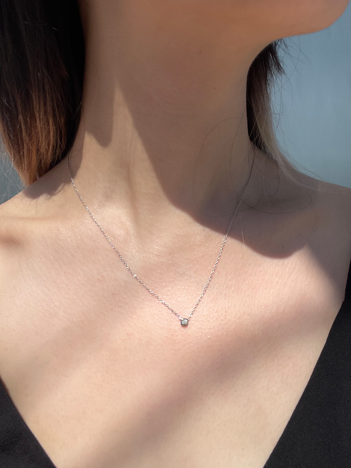 Close-up model photo showcasing a 925 sterling silver solitaire necklace on a neckline, highlighting the subtle scale and sparkle of the 0.04 Ct cushion-shaped Canadian diamond in its miracle plate bezel setting.