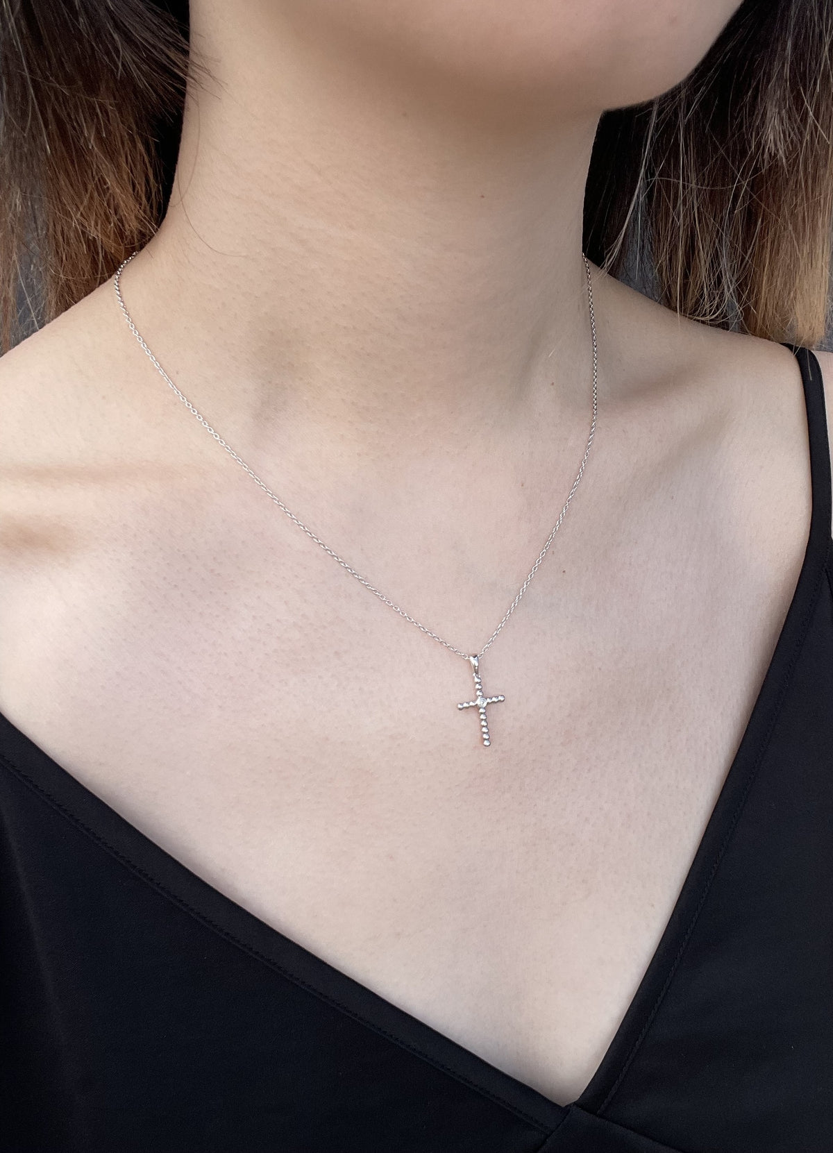 Model wearing a sterling silver beaded cross pendant necklace, featuring a central Canadian diamond accent and a delicate cable chain against a black top.