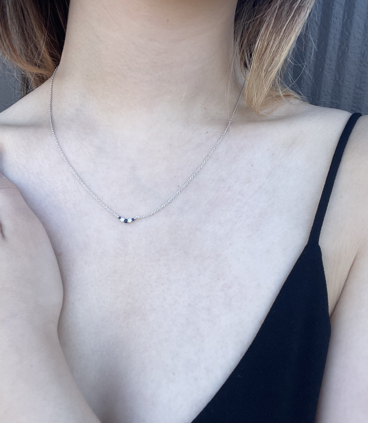 Close-up model photo showcasing a 925 sterling silver 3mm V-shaped curve necklace on a neckline, highlighting how the alternating blue sapphire and Canadian diamond curved setting sits against the skin.