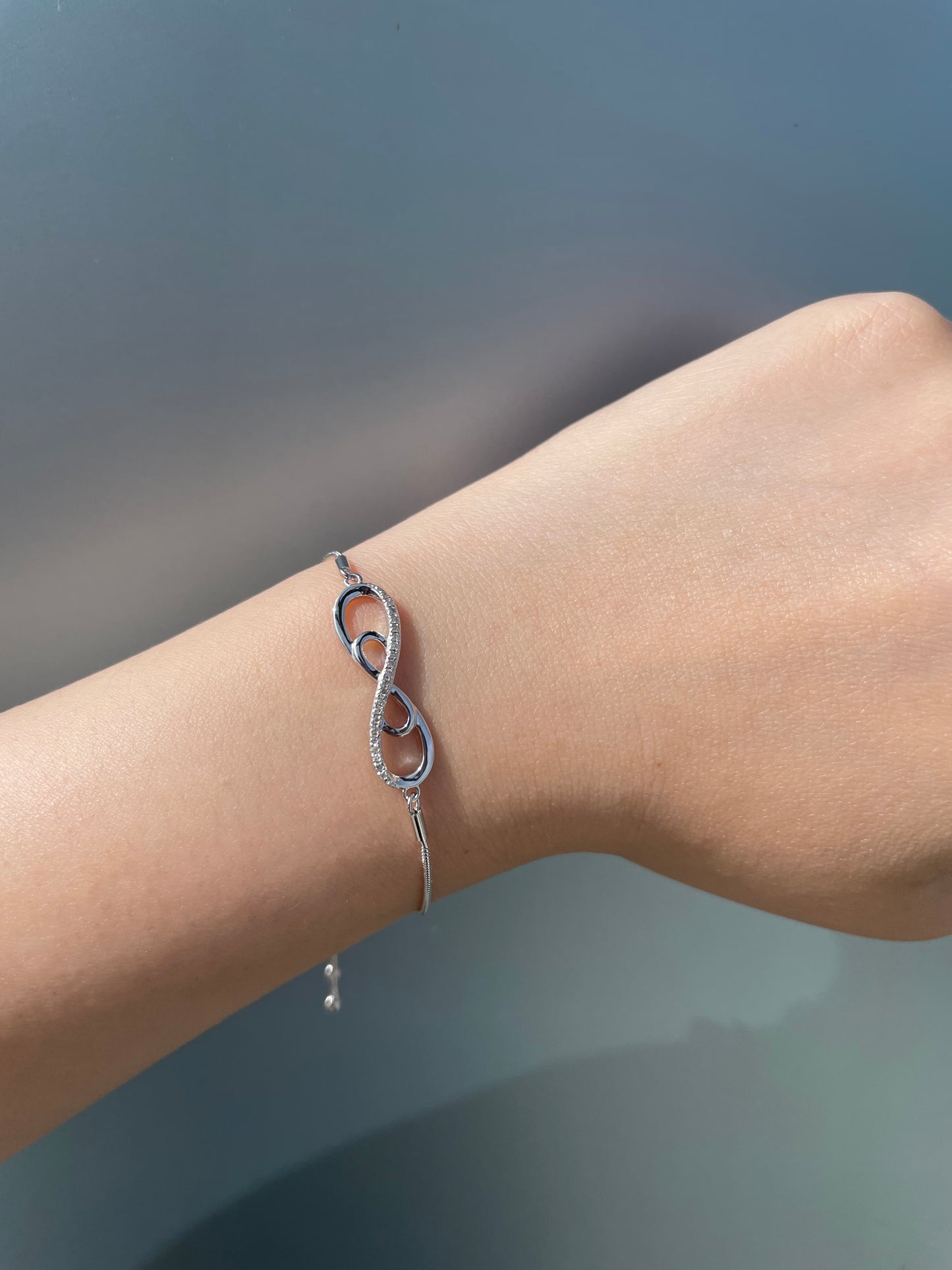 925 sterling silver bolo chain bracelet with a double infinity diamond design. Lifestyle shot on a wrist showing the sparkle of Canadian diamonds and the adjustable silver chain.