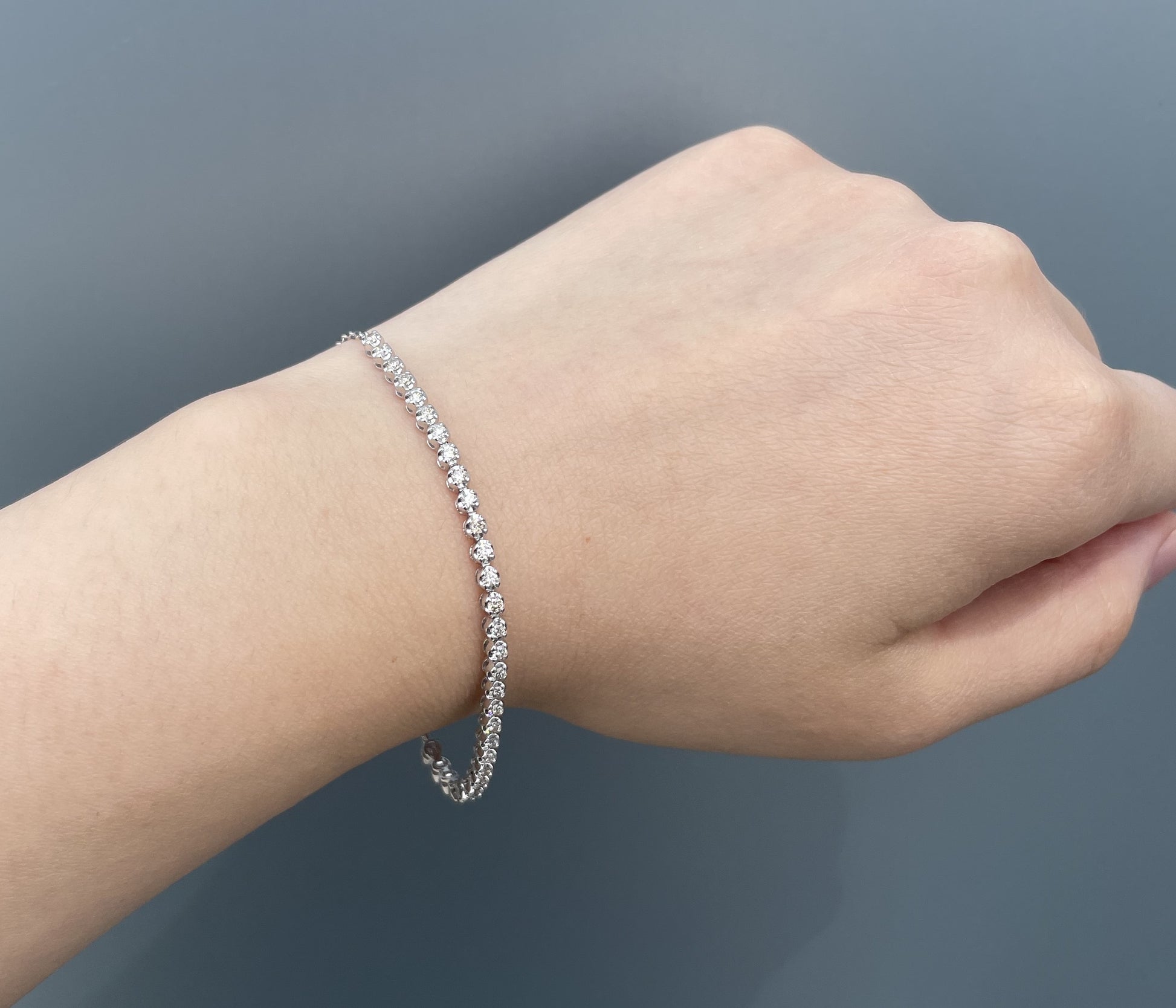 Model wearing a 10K white gold 0.76 Cttw round brilliant cut Canadian diamond half tennis bracelet on wrist.