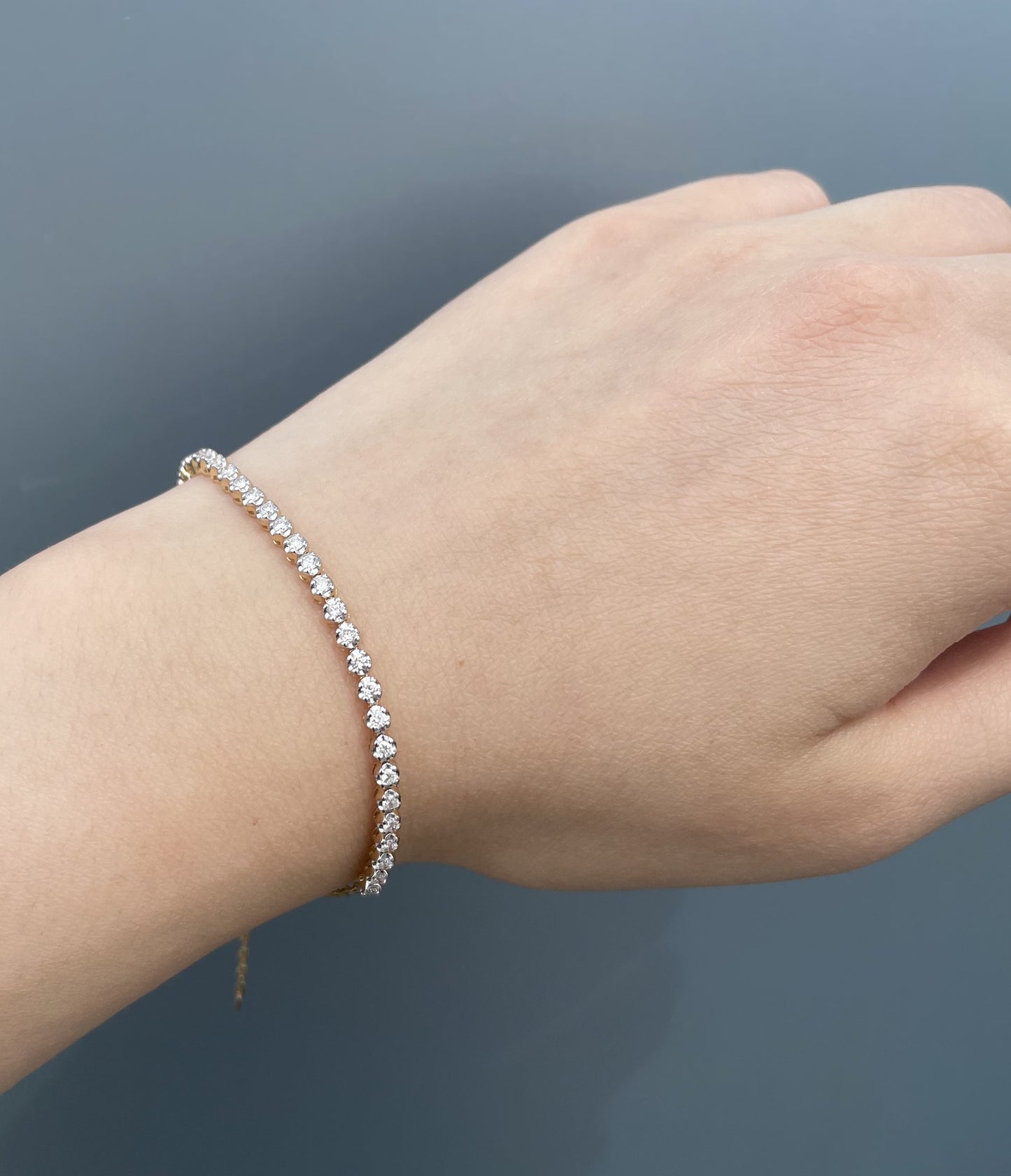 Model wearing a 10K yellow gold 0.76 Cttw round brilliant cut Canadian diamond half tennis bracelet on wrist.