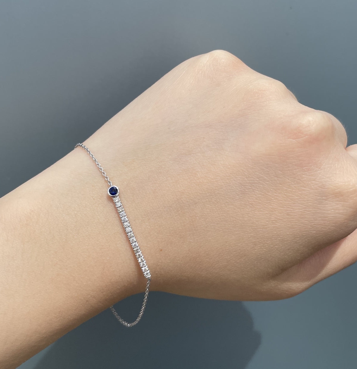 Model wearing a sterling silver blue sapphire and 0.24 cttw Canadian diamond line bracelet on wrist.