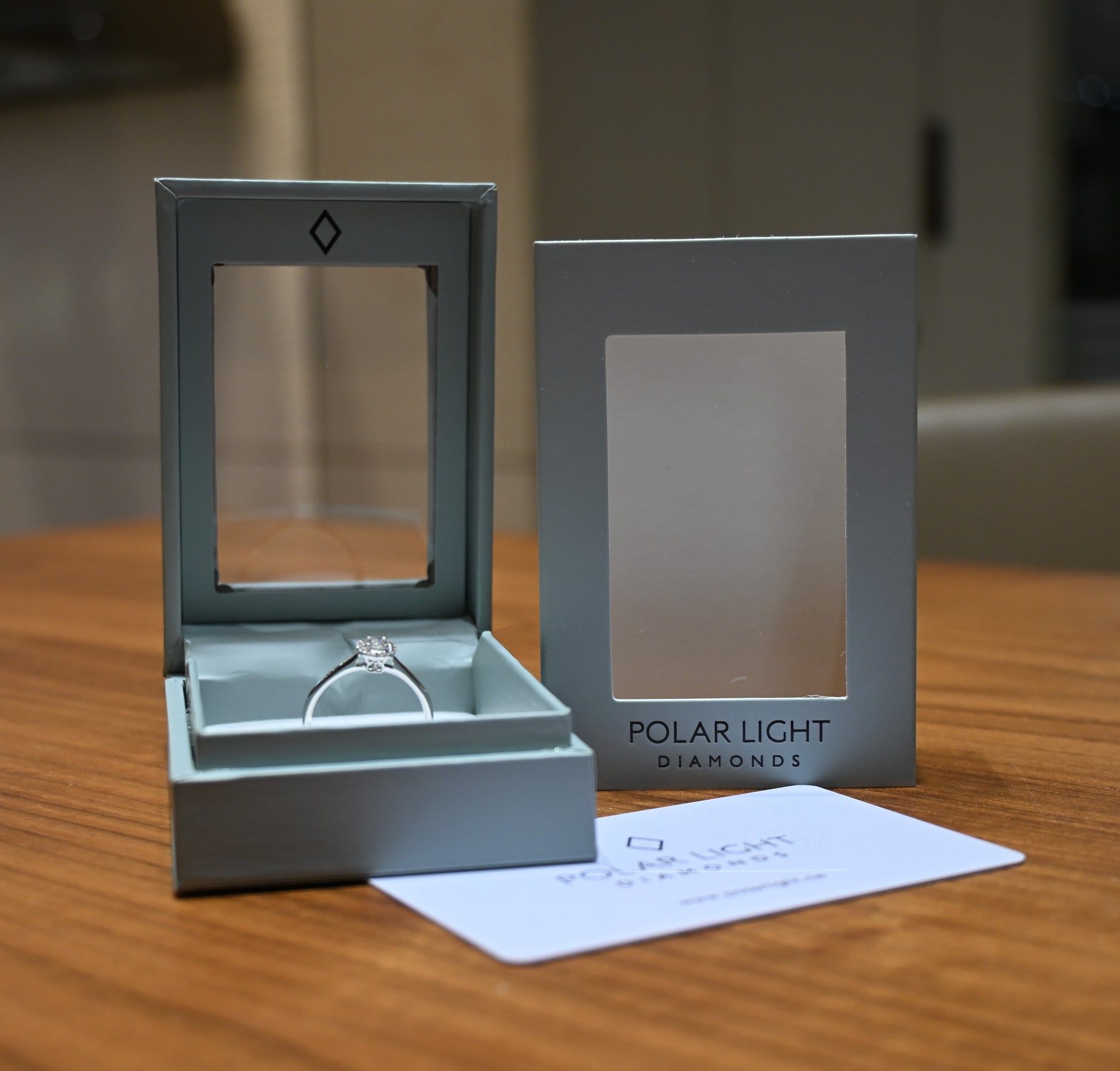 Canadian Diamond halo ring in a 'Polar Light Diamonds' box on a wooden surface