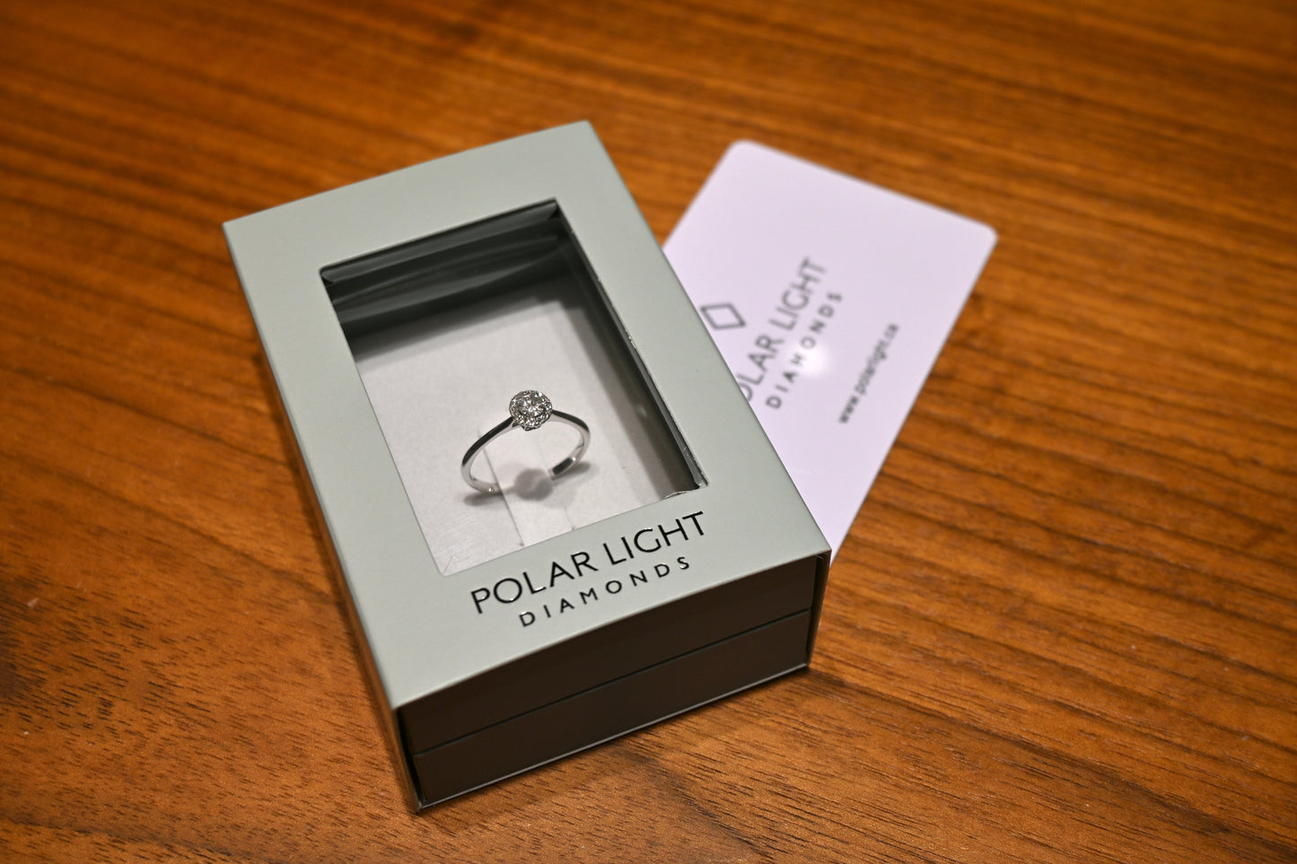 Canadian Diamond halo ring in a 'Polar Light Diamonds' box on a wooden surface