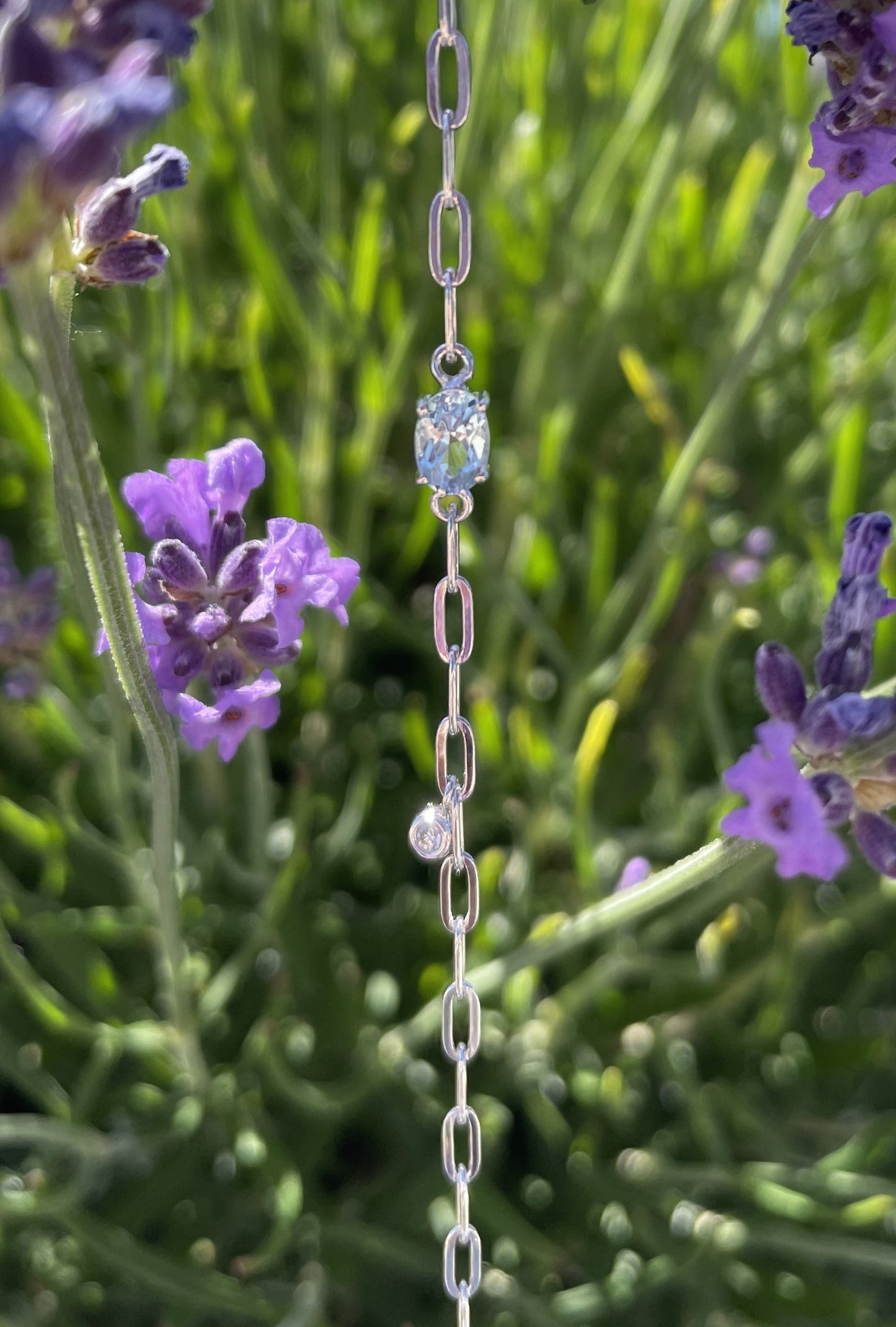 925 Sterling Silver 6x4MM Natural Aquamarine and Canadian Diamond Paperclip Bracelet close up against a background of lavender flowers