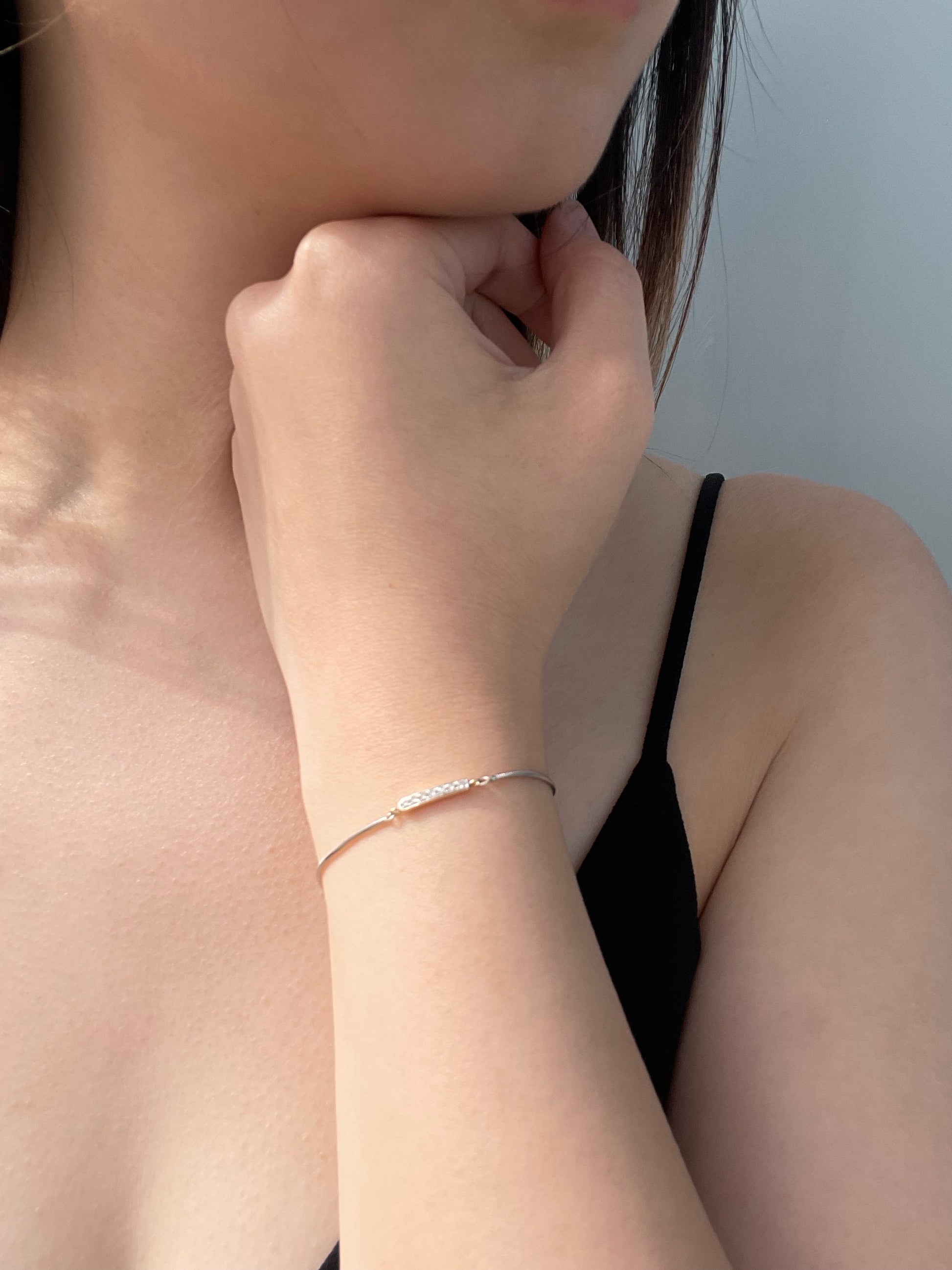 Close-up model photo showcasing a 925 sterling silver and 10K yellow gold bar adjustable bolo bracelet on a wrist, highlighting the delicate two-tone design featuring a horizontal 10k yellow gold bar set with 0.10 Cttw brilliant Canadian diamonds.