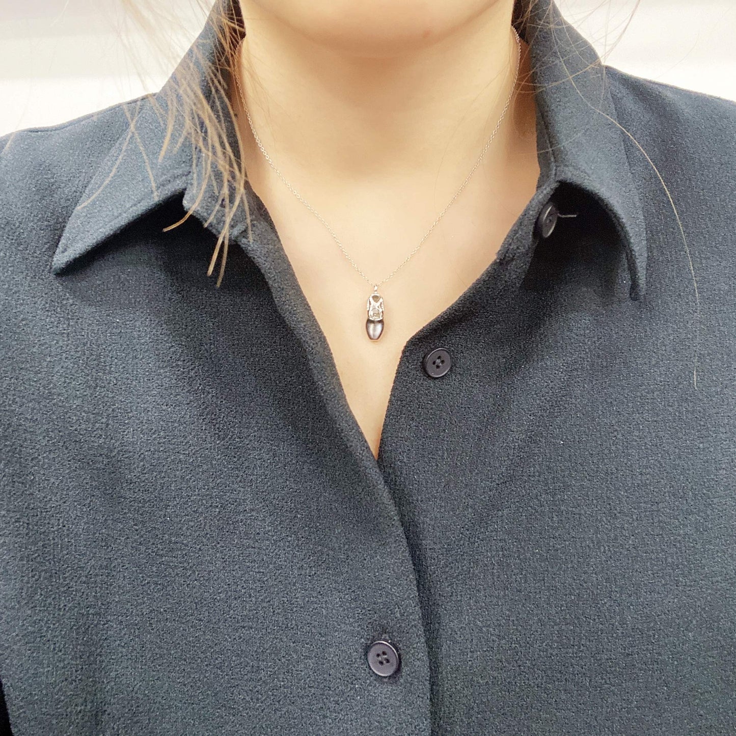 Model wearing a Sterling silver ballet slipper pendant featuring a round brilliant cut, canadian diamond in the center.