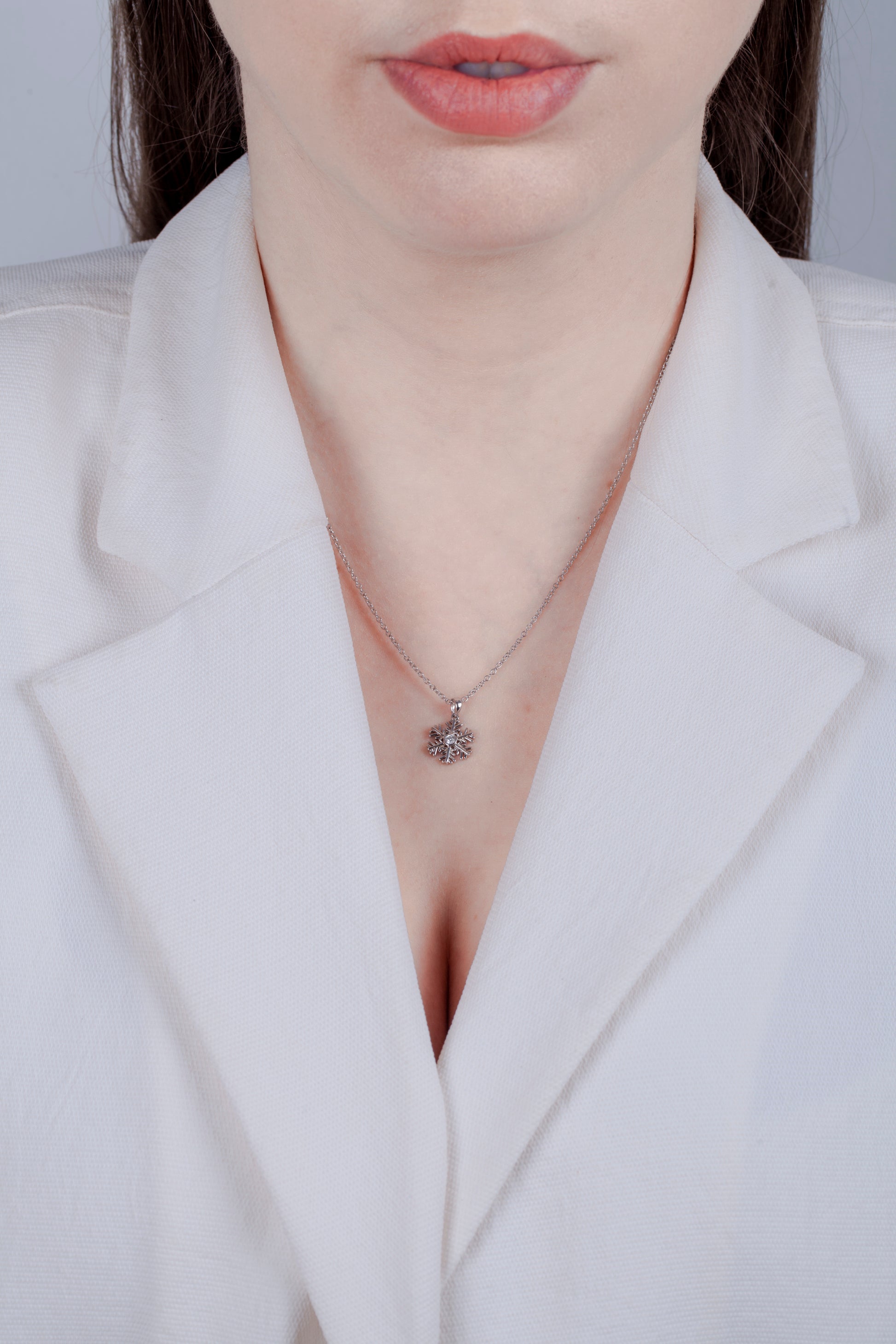 Model with white blazer wearing 925 Sterling silver 0.06 carat Canadian diamond snowflake pendant on a rolo chain, showcasing a minimalistic look.