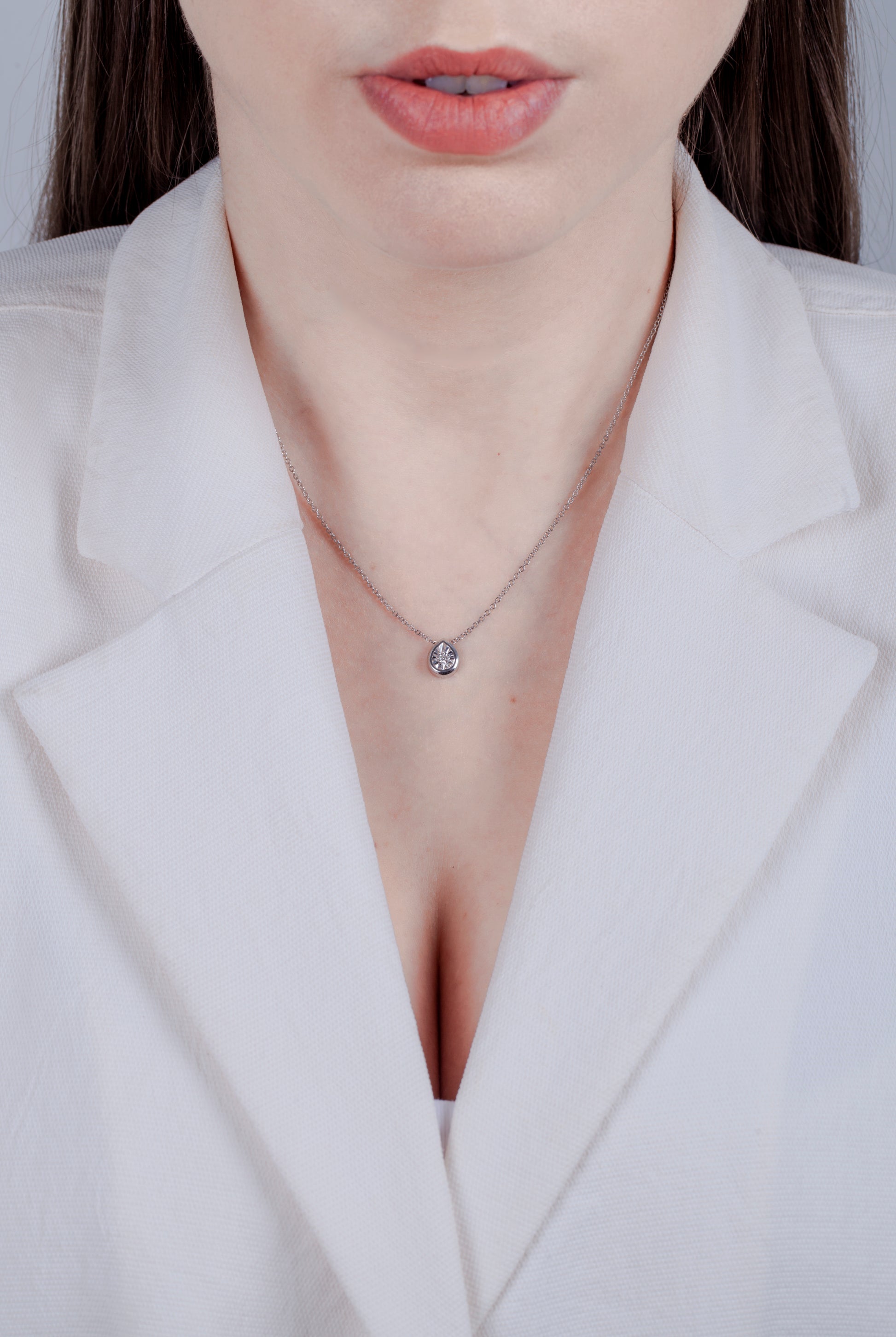 model wearing  a Sterling silver pear shaped pendant featuring a round brilliant cut, canadian diamond set in a miracle illusion setting. 