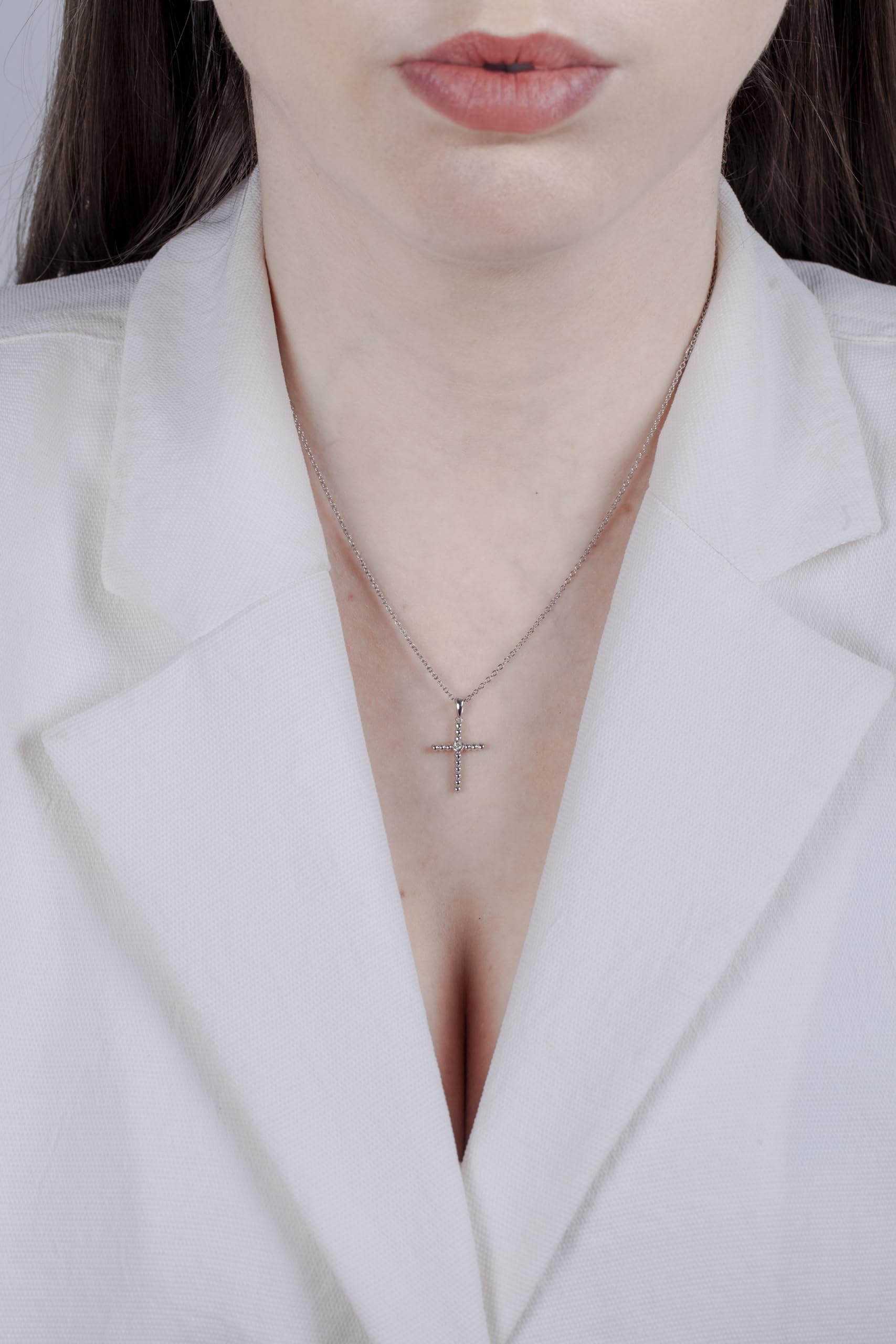 Model wearing a Sterling silver cross pendant featuring a round brilliant cut, canadian diamond in the center.