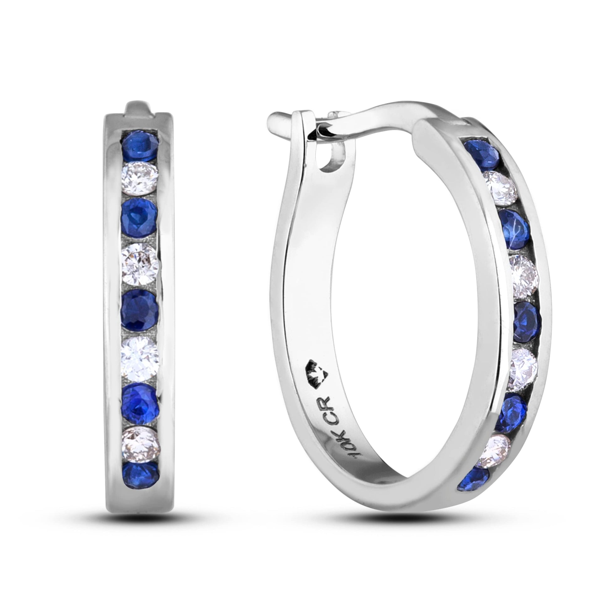 A pair of 10K white gold huggie hoop earrings featuring an alternating channel-set design of 1/6 Cttw blue sapphires and 1/10 Cttw natural diamonds. The earrings are designed with a secure latch back post for a comfortable, seamless fit.