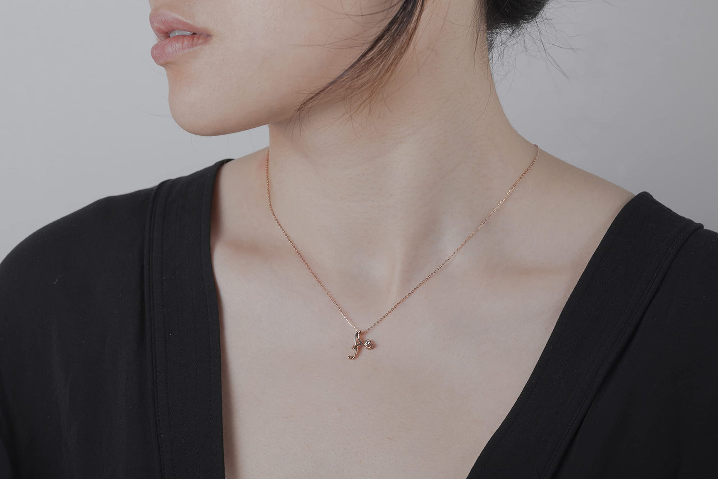 Woman wearing a necklace with a Canadian diamond script letter B pendant, the delicate chain resting just below the collarbone, highlighting the elegant script letter design.
