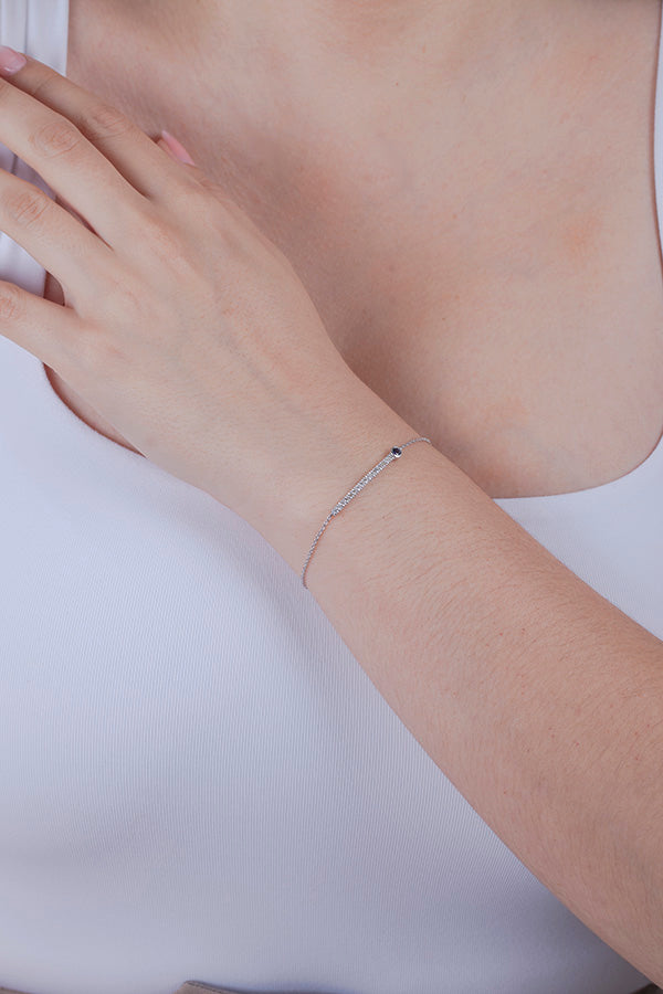 Silver bracelet with diamond and sapphire on a person's wrist against a white background