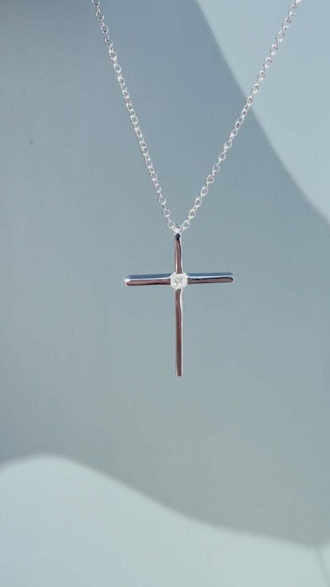 Product showcase video for the .925 Sterling Silver 1/8 Cttw Canadian Certified Diamond Solitaire Thin Cross Pendant Necklace. Includes close-up views of the delicate cross pendant set with a natural solitaire Canadian diamond (H-I color, SI2-I1 clarity), along with an on-model view demonstrating the 16"-18" chain fit and scale.