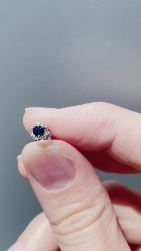 Product showcase video for the .925 Sterling Silver 1/3 Cttw Blue Sapphire & 1/10 Cttw Diamond Petite 0.45cm Halo Style Pushback Stud Earrings. Features close-ups of the central blue sapphire surrounded by a diamond halo (H-I color, SI2-I1 clarity), pushback post detail, and an on-model view showcasing the 0.45cm scale on the ear.