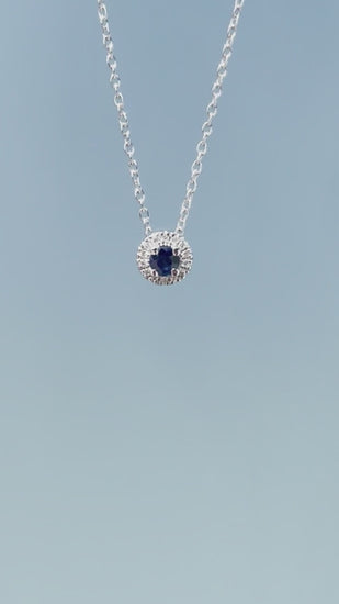 Product showcase video for the .925 Sterling Silver 1/10 Cttw White Diamond & Blue Sapphire 1/4" Halo Pendant Necklace. Includes close-up details of the central sapphire surrounded by a sparkling diamond halo (H-I color, SI2-I1 clarity) and an on-model view demonstrating the 16"-18" chain length.