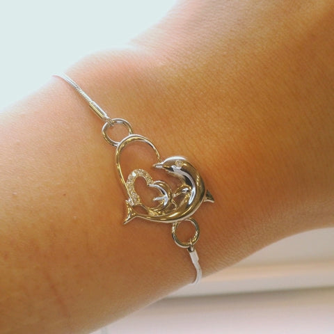 Close up of dolphin and heart Canadian diamond sterling silver bolo bracelet on a wrist with turning motion for easy view of adjustable clasp and details.