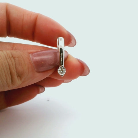 Close-up video of a silver hoop earring with a solitaire diamond, rotating to show the sparkle and setting