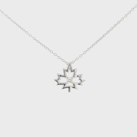 Sterling silver maple leaf charm with solitaire Canadian diamond in the middle in a 4 prong setting, hanging on a rolo chain rotating, showing the design and sparkle of the pendant.