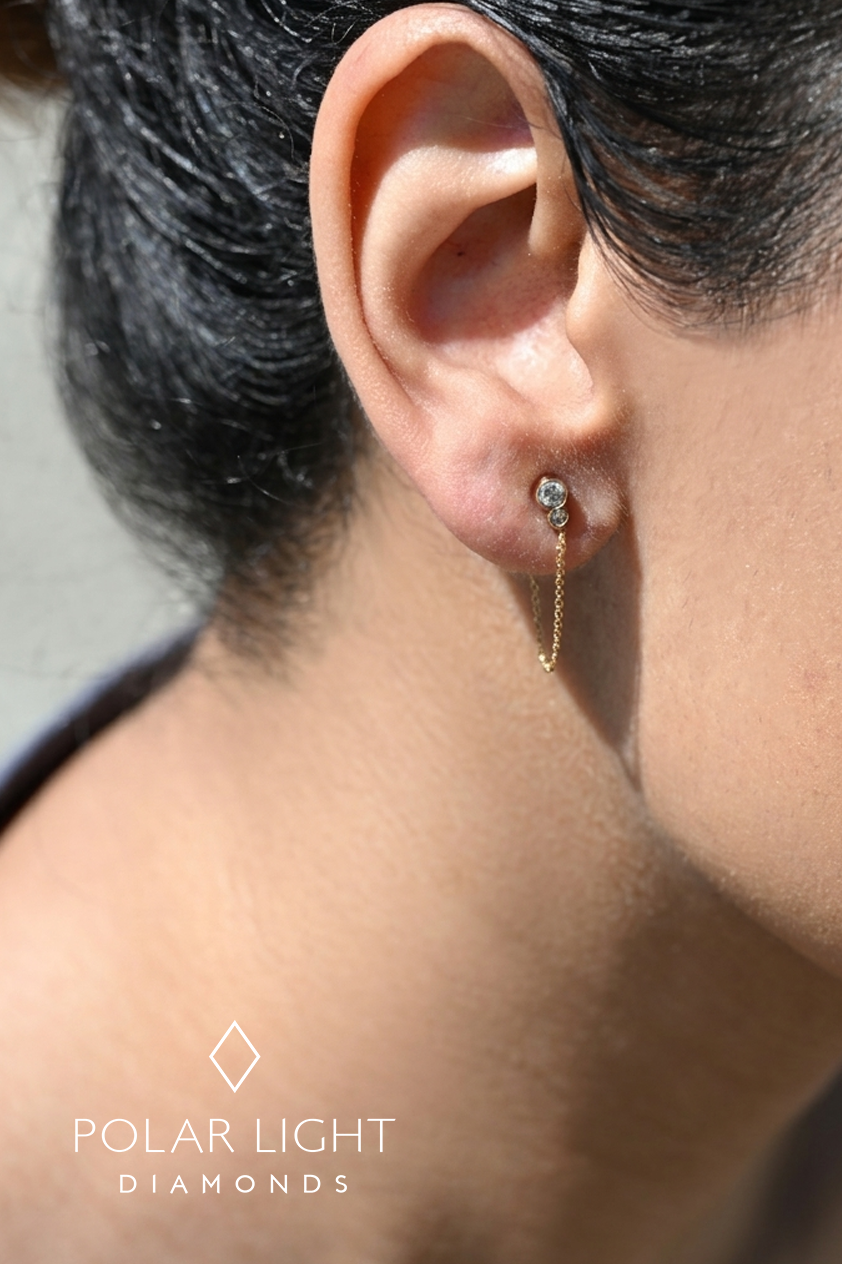 Close up of model wearing 10k yellow gold stud earring with chain for size reference.